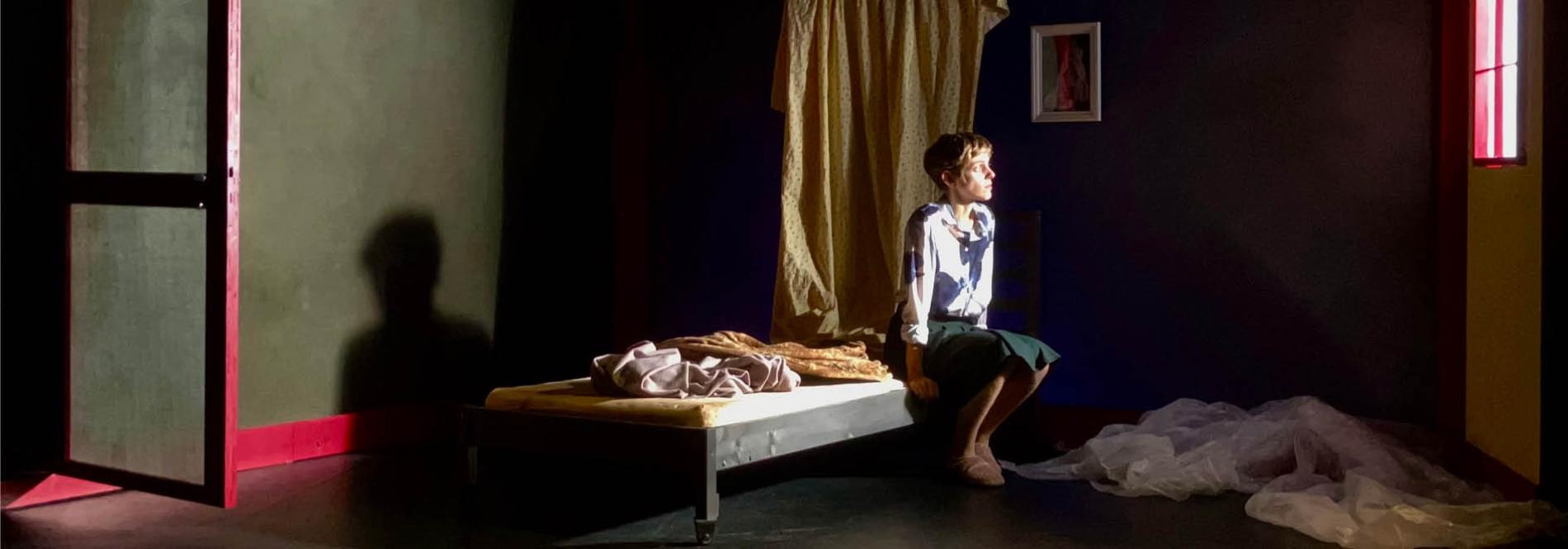 Théâtre - une comédienne assise sur un lit